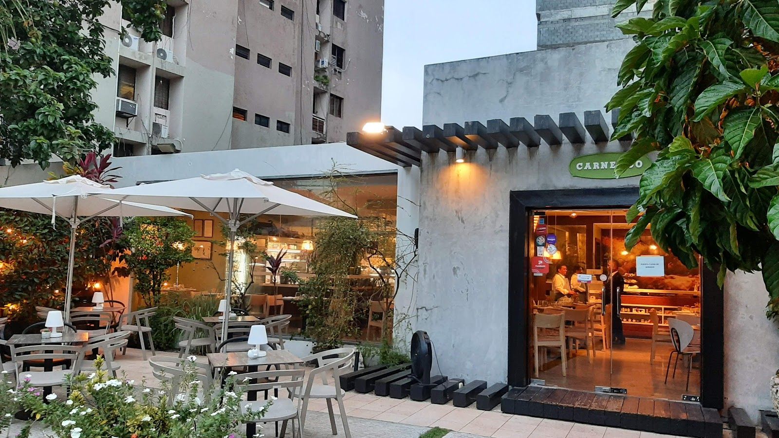 Salón del restaurante en hora dorada — mesas, gente compartiendo, ambiente urbano cálido